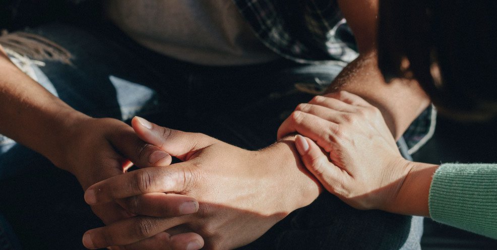 One person is gently holding the hands of another as a sign of support after a suicide in Arlington, TX